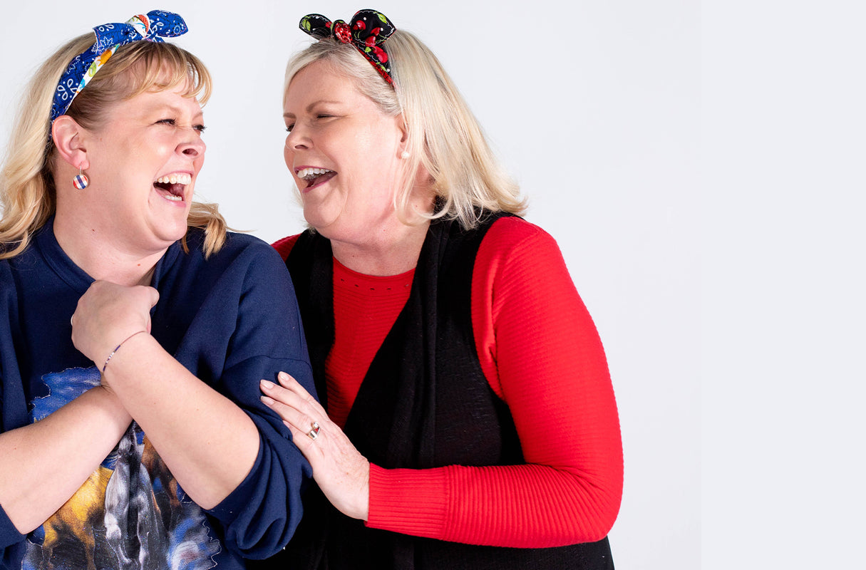 2 women laughing together while wearing pinups